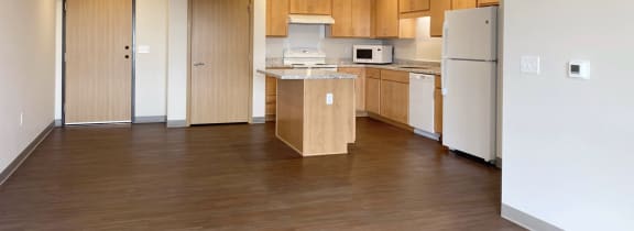 an empty kitchen with wood flooring and white appliances