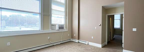 A room with a carpet floor, a ceiling fan, and a window with blinds.