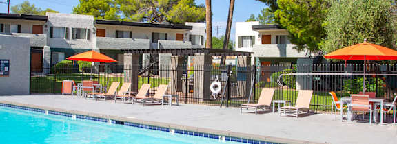 A swimming pool surrounded by a poolside area and buildings.