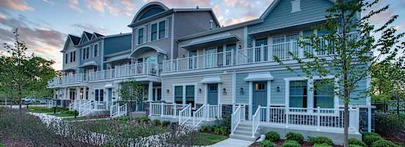 A large, two-story house with a wrap-around porch and a well-maintained lawn.