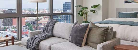 A bedroom with a large window overlooking a cityscape.
