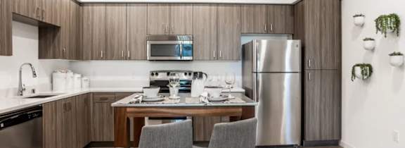 A modern kitchen with a dining table and two grey chairs.