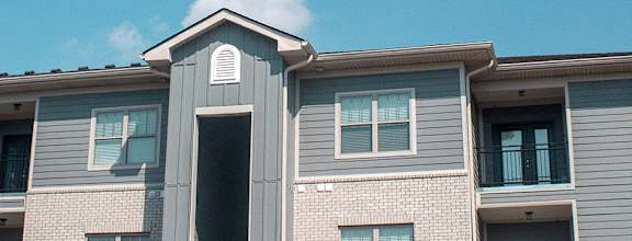 A grey building with a black pole in front.