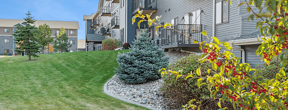 A grey apartment building with a green lawn in front.