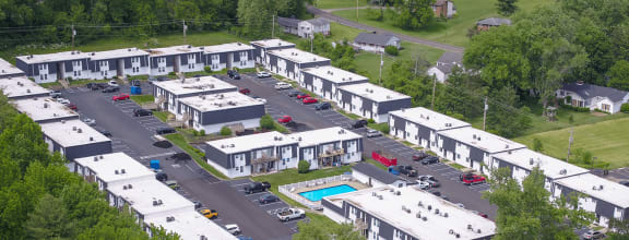 an aerial view of an apartment complex with a pool and parking lot