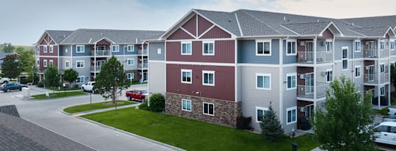 Apartment complex with a red car parked in front.