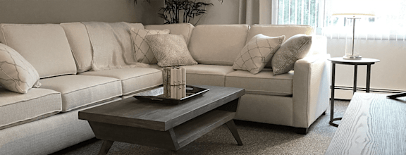 A white sofa with a wooden coffee table in front of it.