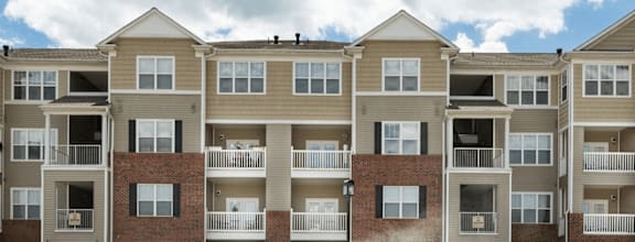 Apartment building with balconies and windows under a blue sky.