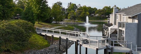 a bridge leading to a pond with a fountain