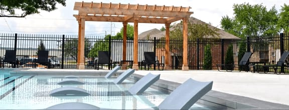 a swimming pool with chairs in front of a fence