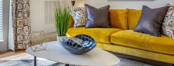a living room with a yellow couch and a table