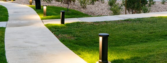 Lite Pathway with grass to apt buildings Units Available in Colorado Springs, CO | Copper Range Apartment Homes