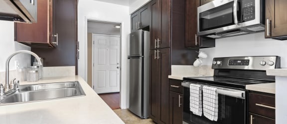A kitchen with dark wood cabinets and white countertops