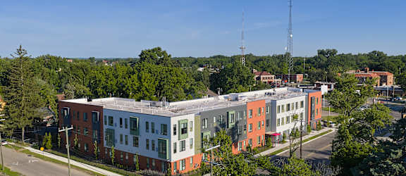 A large building with a red and green facade is surrounded by trees.