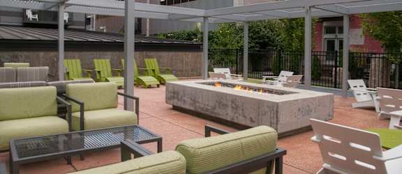 A patio with a fire pit and chairs.