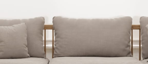 a row of grey cushions on a wooden bench