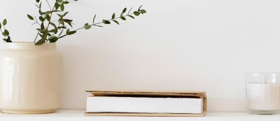 a white desk with a white vase and a gold watering can