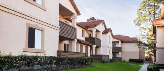 a row of apartment buildings with a green lawn in the foreground