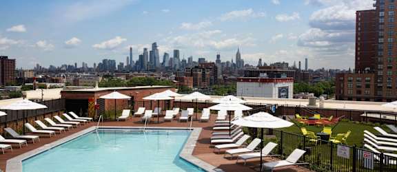 a pool on the roof of a hotel with the city skyline in the background