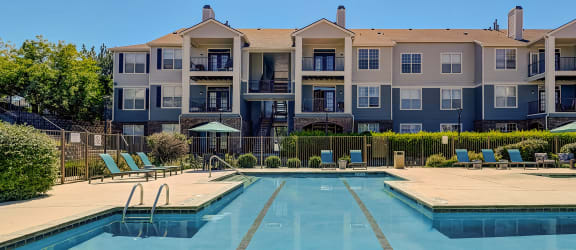 an apartment building with a pool and chairs in front of it