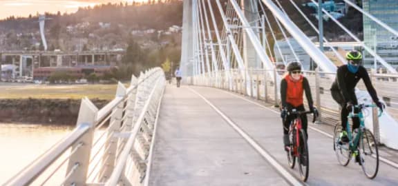 two people riding bikes on a bridge