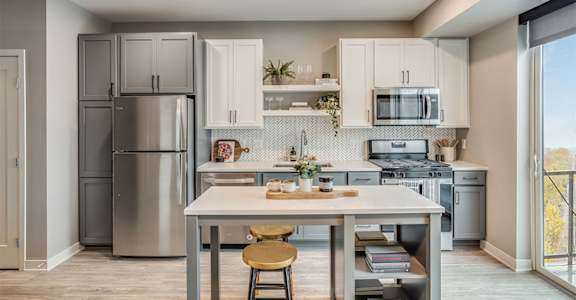 A kitchen with a table and chairs in front of a refrigerator and oven.