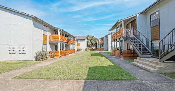 A row of modern apartment buildings with a clear blue sky above at The Marq in Shreveport, LA