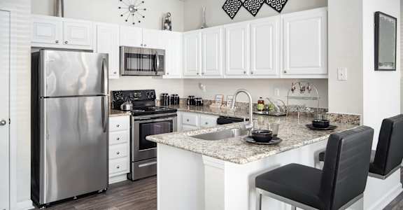 A kitchen with a refrigerator, oven, and sink.