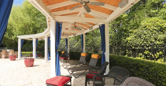 a covered patio with wicker chairs and a ceiling fan