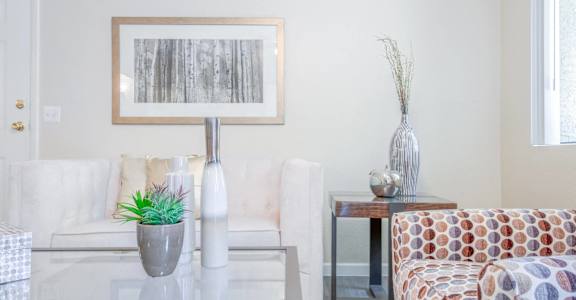 A living room with a couch, a coffee table, and a painting on the wall.
