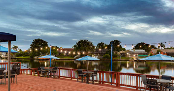 a boardwalk with tables and umbrellas next to a body of water at Waterview at Rocky Point, Florida