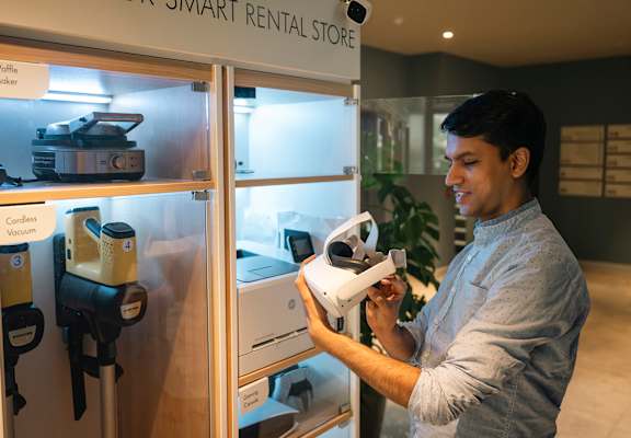 A man is holding a white drone in a smart rental store.