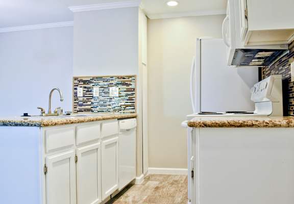 A kitchen with a white fridge and cabinets.
