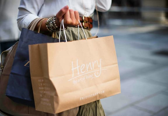a woman holding a paper bag with her shopping bags