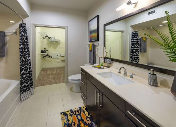 A bathroom with a white sink, large mirror and tiled surround