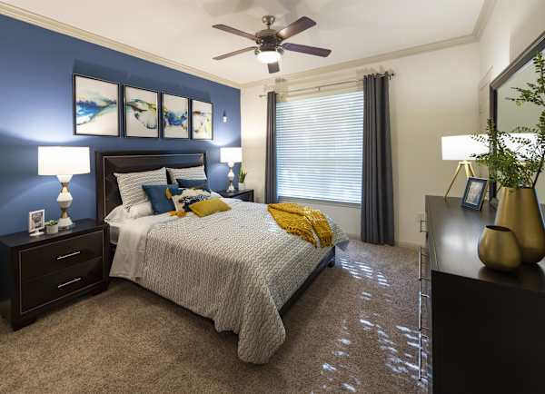 A furnished bedroom with a bed, two nightstands and a ceiling fan