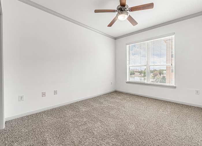 A bedroom with a ceiling fan and blinds on the window