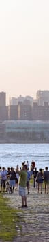 people walking on a path near the water with a city in the background at 34 Berry, Brooklyn, NY