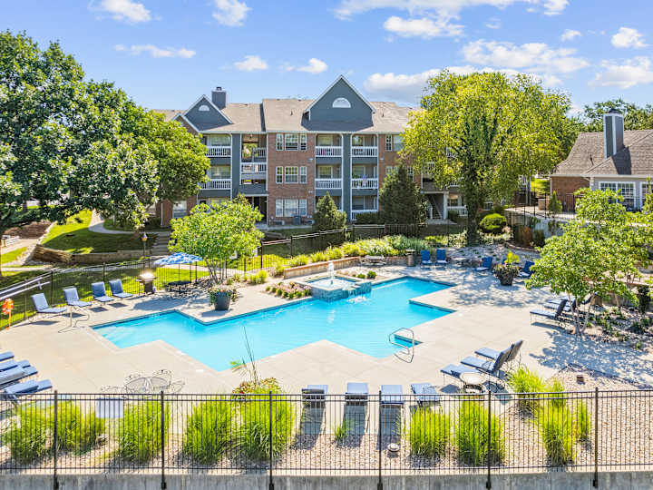Outdoor swimming pool with blue lounge chairs and apartment buildings at Stonebriar