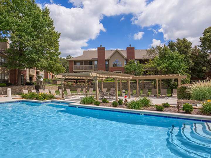 Outdoor swimming pool with a tan pergola and lounge chairs at Highland Park