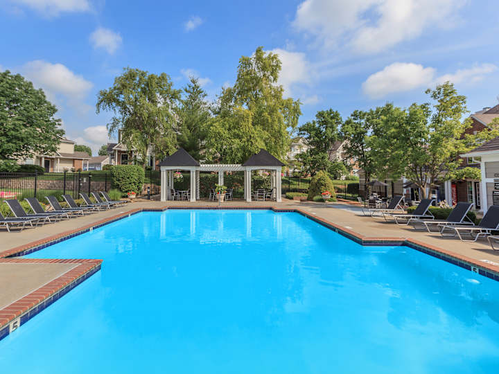 Outdoor swimming pool with lounge chairs and a white pergola at Stonebriar Woods