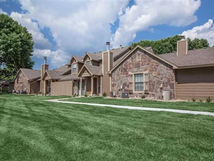 Tan siding and stone townhome exterior with a front lawn at Waterford Place