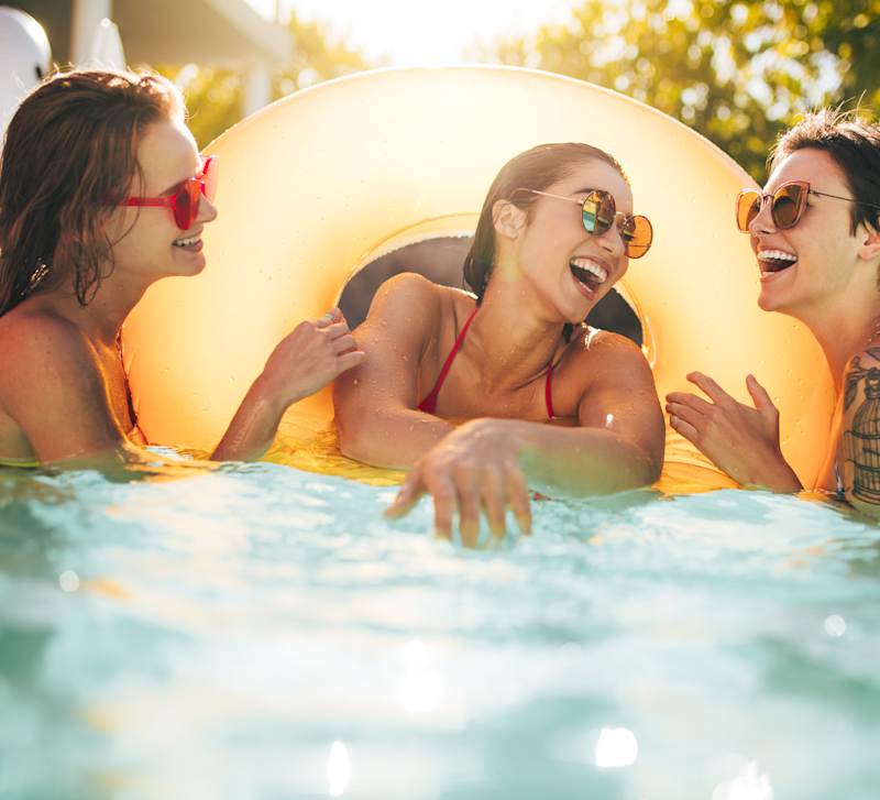 Three residents floating and laughing in the swimming pool