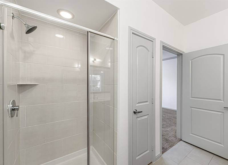 A bathroom with a glass shower door and white tiled walls