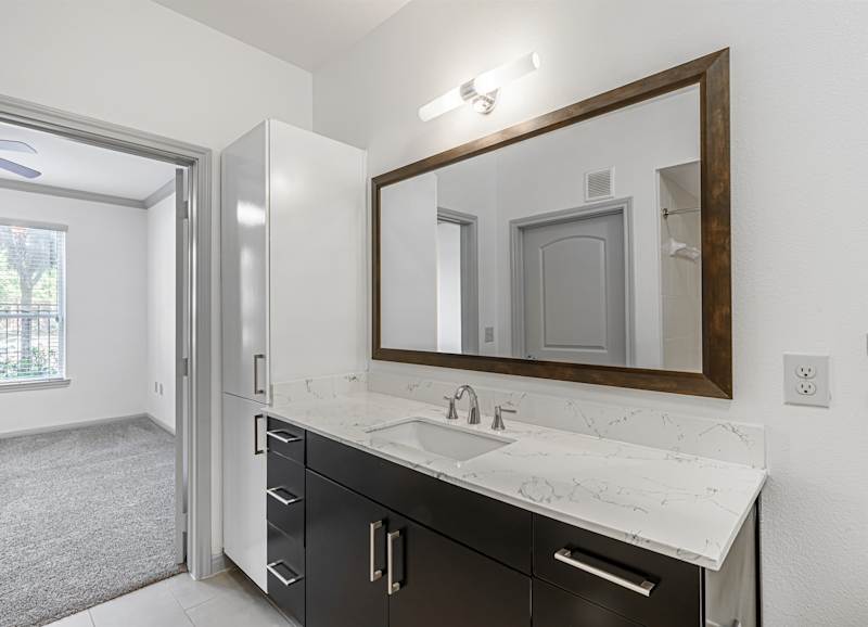 A bathroom with a sink, mirror and dark cabinets
