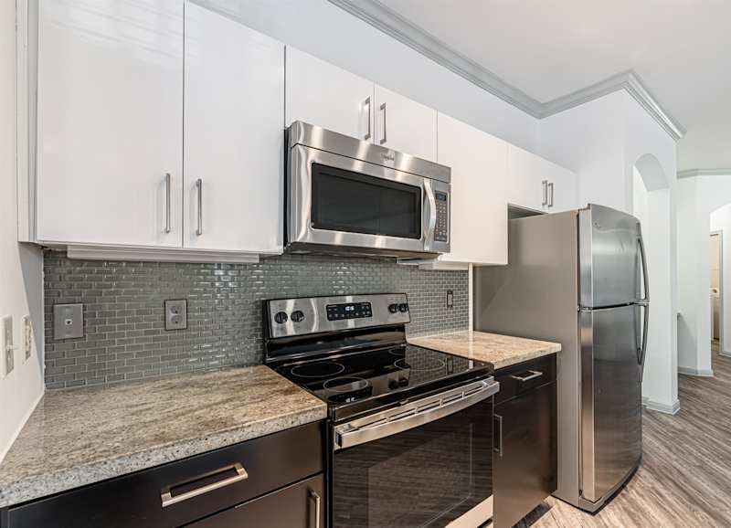 A kitchen with a stove, microwave and refrigerator