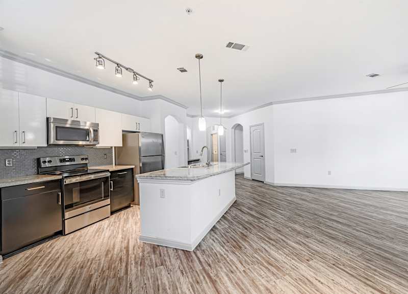A kitchen with black appliances and wood-look floors