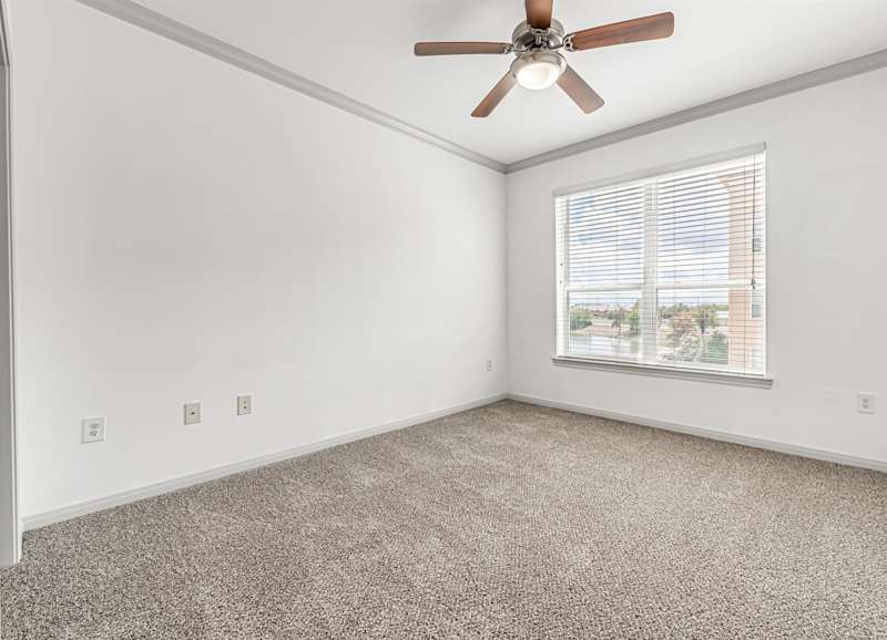 A bedroom with a ceiling fan and blinds on the window