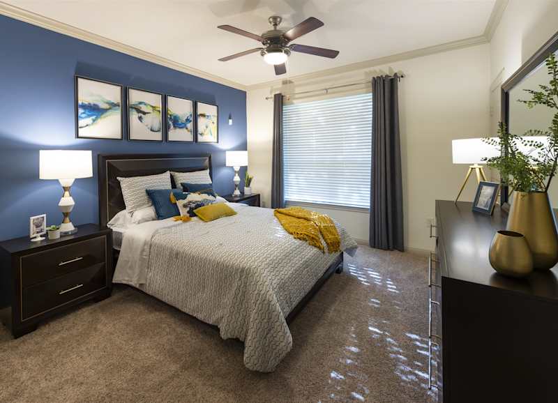 A furnished bedroom with a bed, two nightstands and a ceiling fan