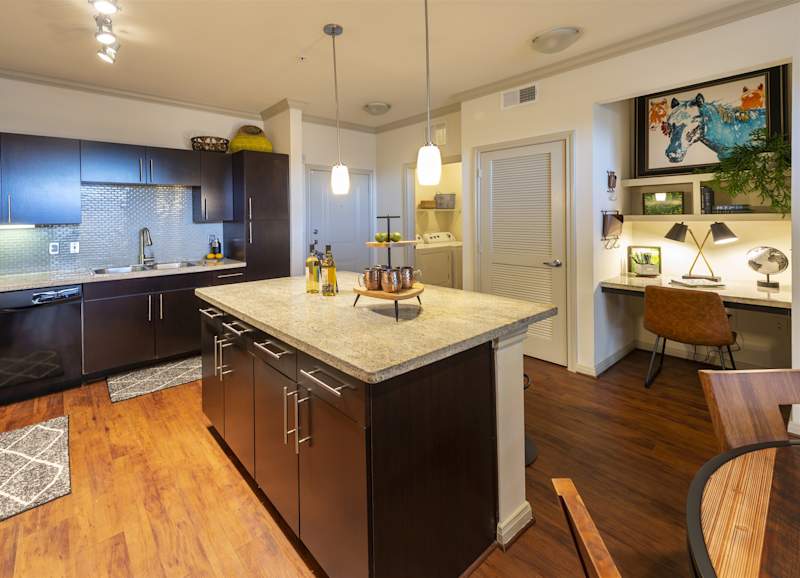 A kitchen with a long island and wood-look flooring